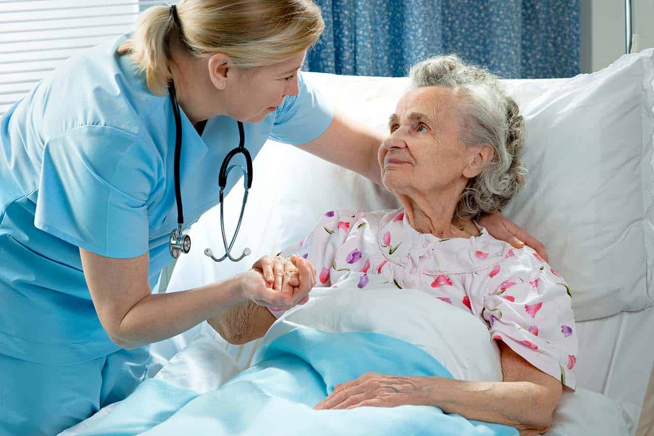 Nurse holding an older patient's hand